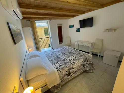 Dormitorio con cama, escritorio y TV en Chiara rooms, en Vernazza