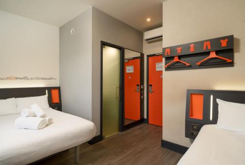 a room with two beds with orange and green doors at easyHotel Milton Keynes in Milton Keynes