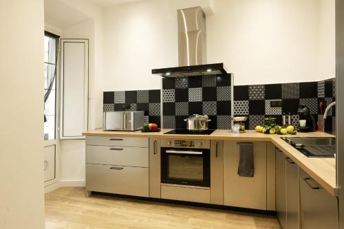 - une cuisine avec du carrelage noir et blanc sur le mur dans l'établissement Appart, à Bastia