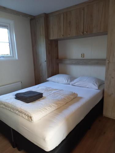 een slaapkamer met een groot bed met witte lakens en een raam bij Vakantieverblijf Uit en Thuis in Biggekerke