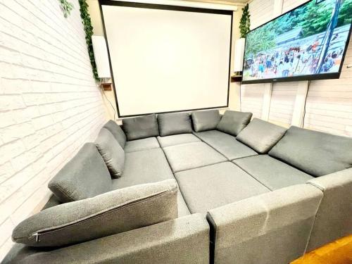 a couch sitting in a room with a blank screen at 舞浜の一軒家 3寝室 6ベッド 東京ディズニーリゾートまで車5分 東京駅から好アクセス in Urayasu
