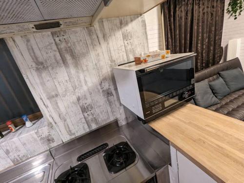 a kitchen with a microwave on top of a counter at 【2024/2月OPEN! 一軒家貸切】東京ディズニーリゾートまで車5分、徒歩20分 in Tokyo