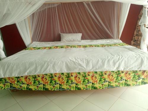 Una cama grande con un edredón blanco y flores. en African Tent Resort, en Kabale