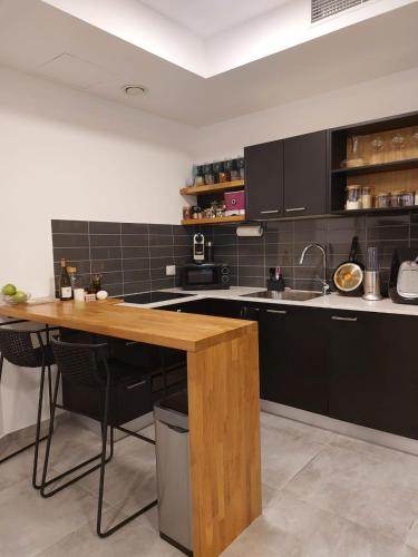 a kitchen with black cabinets and a wooden table at Gindi Tower Apartments TLV in Tel Aviv