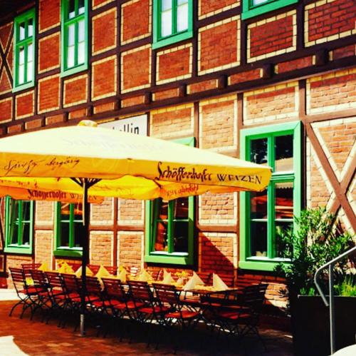a table and chairs under an umbrella in front of a building at Pension und Appartements alter Fehrbelliner Bahnhof in Fehrbellin