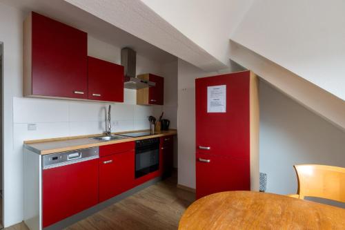 a kitchen with red cabinets and a wooden table at Pension für Monteure in Leipzig in Leipzig