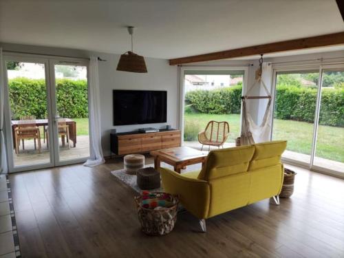 uma sala de estar com um sofá amarelo e uma televisão em Maison avec jardin au pied du Viaduc de Millau em Creissels
