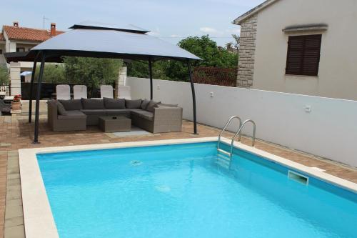 a blue swimming pool with an umbrella and a couch and an umbrella at Apartments Kimm II in Poreč