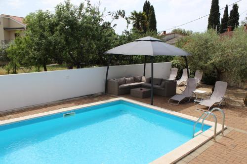 a swimming pool with an umbrella and chairs and a couch and an umbrella at Apartmens Kimm II in Poreč