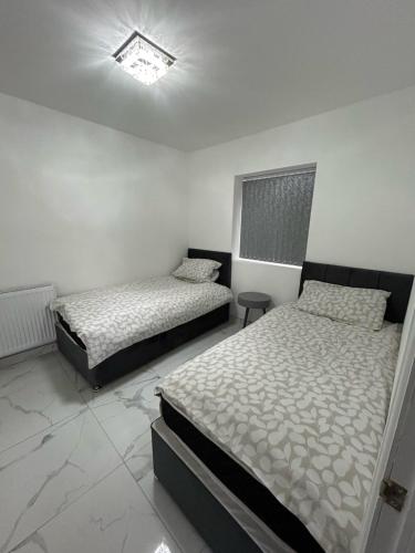 two beds in a room with white walls at Peaceful Studio - Near NEC, BHX Airport. in Birmingham