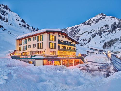 a large building in the snow in front of a mountain at Arlberg Stuben - das kleine, feine Hotel in Stuben am Arlberg