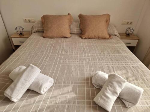 Una cama con tres pares de toallas blancas. en El Atico de Sabadell muy cerca del centro, en Sabadell