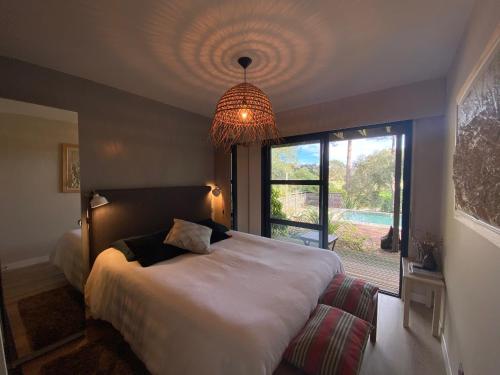 une chambre avec un grand lit et un lustre dans l'établissement Villa 24 Moliets, à Moliets-et-Maa