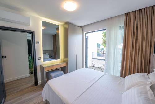 a bedroom with a white bed and a large window at Botanica Boutique Hotel in Ulcinj