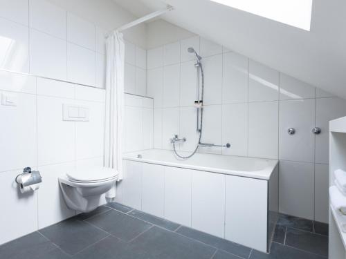 a white bathroom with a toilet and a bath tub at 3,5-Room Sunrise Terrace Haven FR-32 in Wallisellen