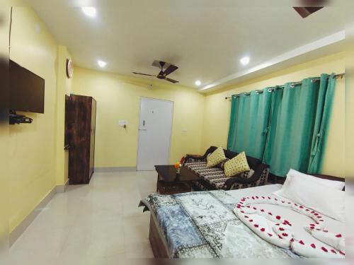 a bedroom with a bed and a couch and a tv at CHARULATA RESIDENCY in Bolpur