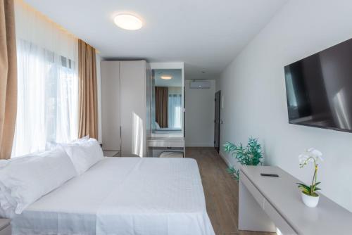 a white bedroom with a white bed and a desk at Botanica Boutique Hotel in Ulcinj