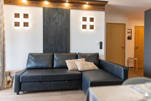 een woonkamer met een zwarte leren bank bij New high-end apartment 6P3BR - Haut Combloux in Cordon