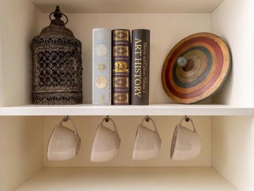 a shelf with books and a clock and a plate at Howman House in Cheltenham