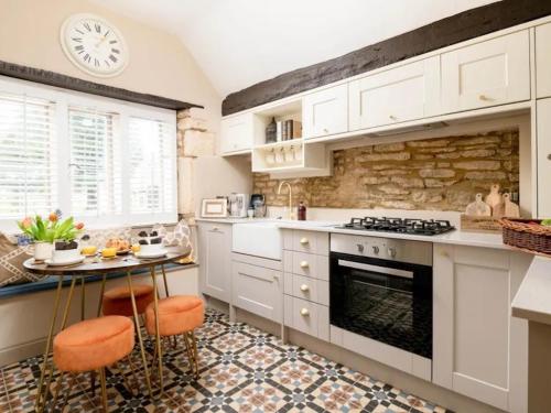 a kitchen with white cabinets and a stone wall at Howman House in Cheltenham