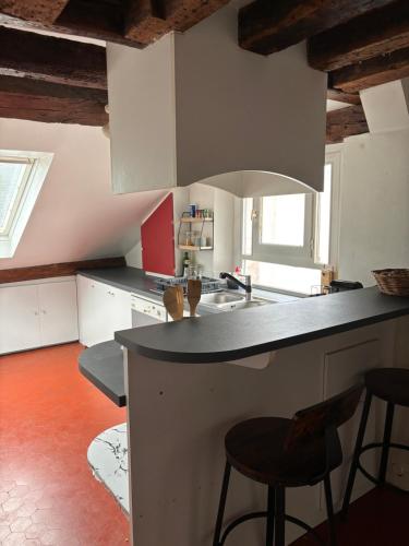 - une cuisine avec un comptoir et quelques tabourets dans l'établissement Appartement atypique à deux pas du Château de Versailles, à Versailles