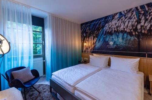 a bedroom with a large bed and a chair at Arthotel ANA Aura in Aystetten