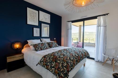une chambre avec un grand lit avec un mur bleu dans l'établissement Le Léon - Appartement vue montagne Porto Vecchio, à Porto-Vecchio