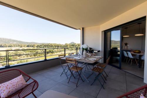 une salle à manger avec une table et des chaises sur un balcon dans l'établissement Le Léon - Appartement vue montagne Porto Vecchio, à Porto-Vecchio