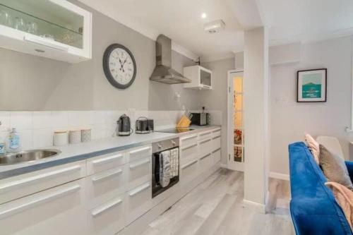 a kitchen with a sink and a clock on the wall at Molokai Snug Best location North South bay Courtyard garden Parking in Scarborough