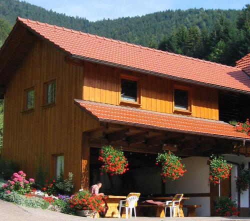 a building with a table and chairs and flowers at Mosertonihof in Elzach
