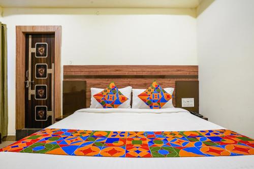 a bedroom with a large bed with a colorful blanket at FabHotel Raj Vihar Residency in Vijayawāda