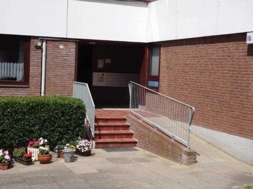 - un bâtiment avec des escaliers et des fleurs devant dans l'établissement Elbe Ferienwohnung Glückstadt Reimer Ahsbahs, à Glückstadt