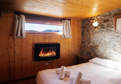 a bedroom with a fireplace and a bed with towels at Can Ricart in Puigcerdà