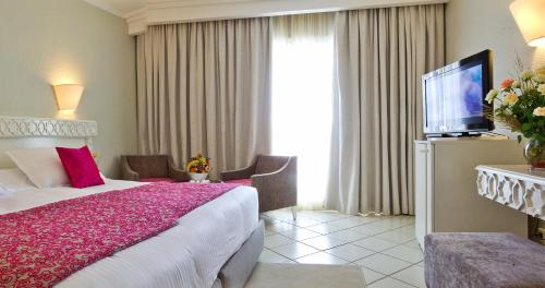 una camera d'albergo con letto e TV di El Mouradi Palm Marina a Port El Kantaoui