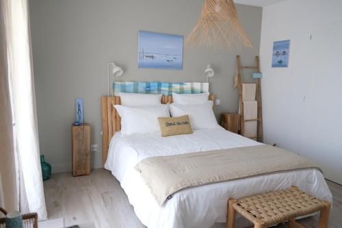 a bedroom with a bed with white sheets and a stool at VILLA PIERARTLOU in Arès