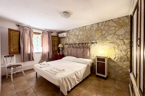 a bedroom with a bed and a stone wall at [Eleganza Rustica In Villa] A 5 minuti dal mare in Tonnara di Bonagia