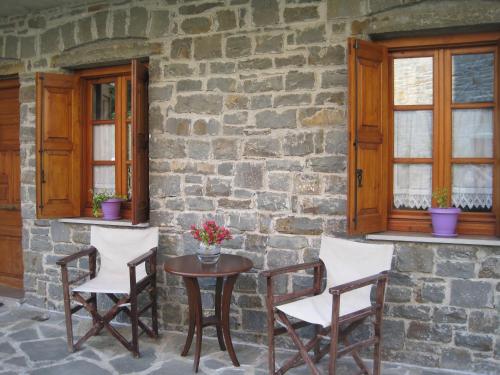 a table and chairs in front of a stone building at Hotel Tymfi in Tsepelovo