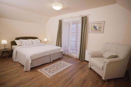 a white bedroom with a bed and a chair at Karlamuiza Country Hotel in Kārļi