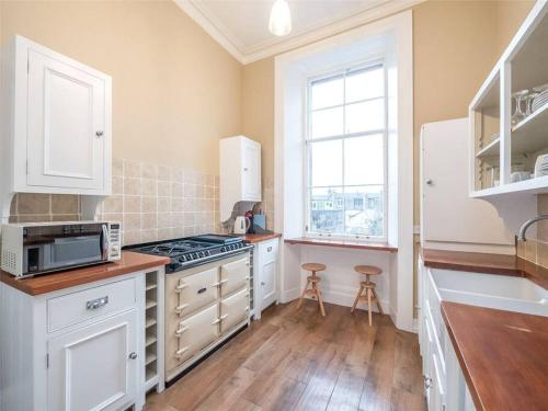 una cucina con armadi bianchi e piano cottura di Beautiful & bright 2 bed flat Murrayfield a Edimburgo