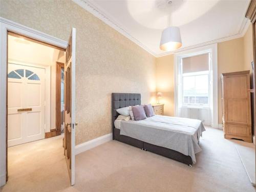 a bedroom with a bed and an open door at Beautiful & bright 2 bed flat Murrayfield in Edinburgh