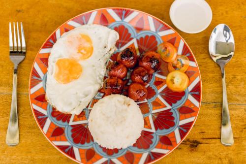 a plate of food with eggs and fruit on a table at Villa Lourdes Resort in Panglao