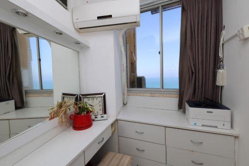 a room with white cabinets and windows and a red vase at קו ראשון לים in Netanya