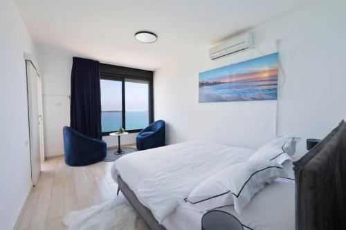 ein Schlafzimmer mit einem Bett und zwei blauen Stühlen in der Unterkunft קו ראשון לים in Netanya