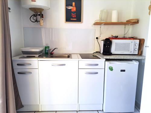 una pequeña cocina con armarios blancos y microondas en Bungalow Java - Bassin Manapany-Les-Bains, en Saint-Joseph