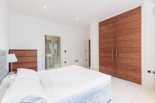 a white bedroom with a large bed and a wooden closet at Hestia Travel London in London