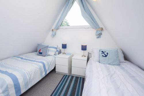 twee bedden in een kleine kamer met een raam bij Chalet One in Deal