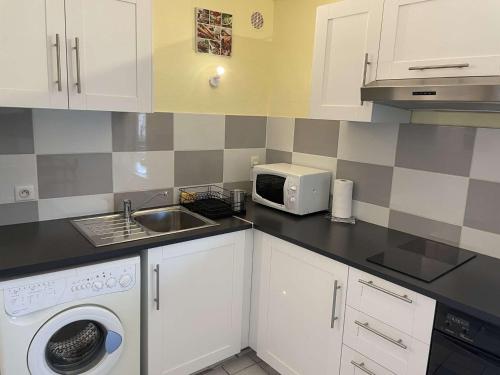 une cuisine avec un évier et un micro-ondes dans l'établissement Charmant T2 avec Balcon et Parking à 800m de la Plage - St Pierre la Mer - FR-1-229D-125, à Fleury