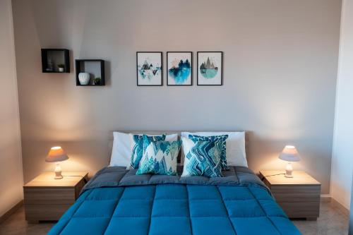 een slaapkamer met een blauw bed met drie foto's aan de muur bij A casa di Vito in Mazara del Vallo