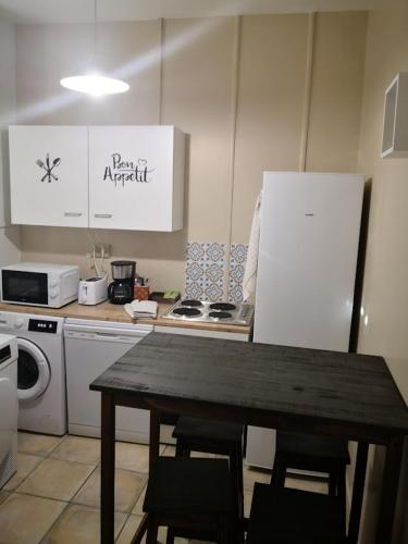 une cuisine avec une table avec des chaises et un réfrigérateur dans l'établissement un lit double dans une chambre dans un appartement de 3 chambres en colocation à proximité du centre ville, à Toulon