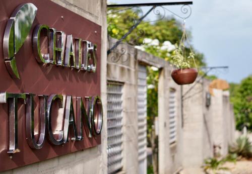 um sinal na lateral de um edifício com um vaso de flores em Chalés Tucano Praia da Pipa - Natureza, Conforto, Tranquilidade em Pipa